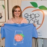New threads: Chilton County Chamber of Commerce Executive Assistant Brittani Ellison shows off the design for the 2014 Peach Jam T-shirt.