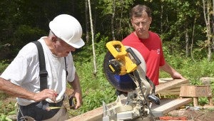 Mike Jordan with Alabama Power Company assists John Watchal to cut boards for the home.